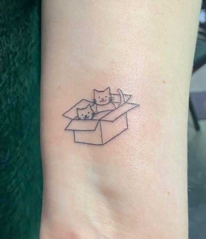 a small tattoo with three cats in a box