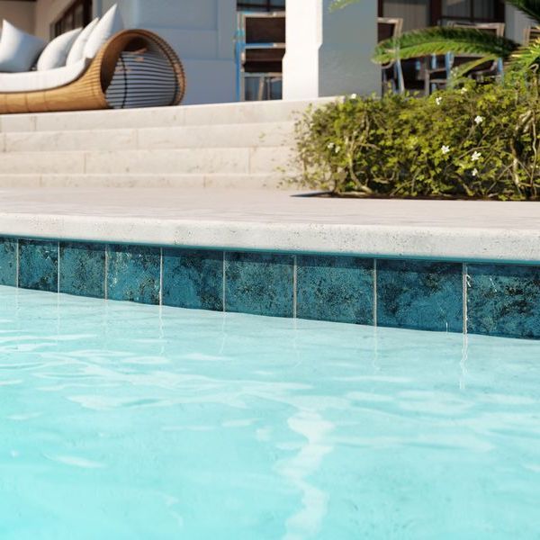 an empty swimming pool with lounge chairs in the back ground and steps leading up to it