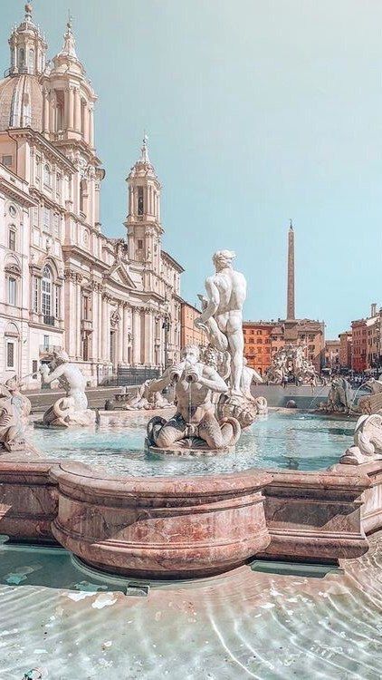 the fountain is surrounded by statues and buildings