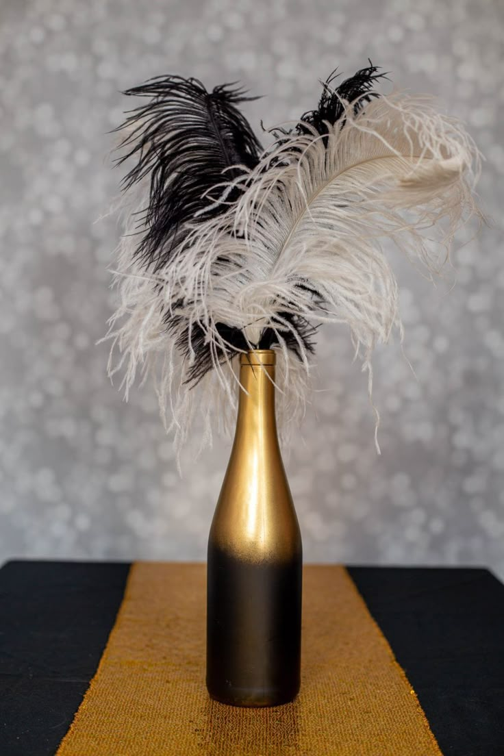 a gold vase with black and white feathers in it