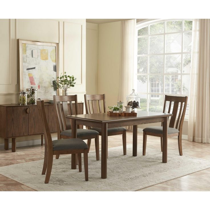 a dining room table and chairs in front of a window