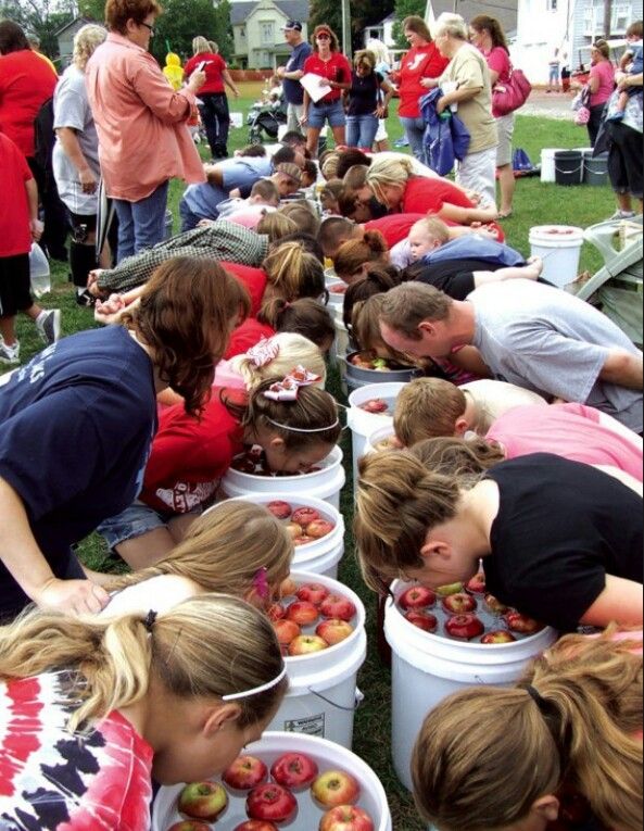 several people are picking apples from buckets on the grass