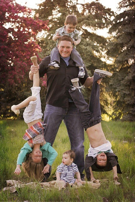 a family is posing for a photo in the grass with their two children on their shoulders