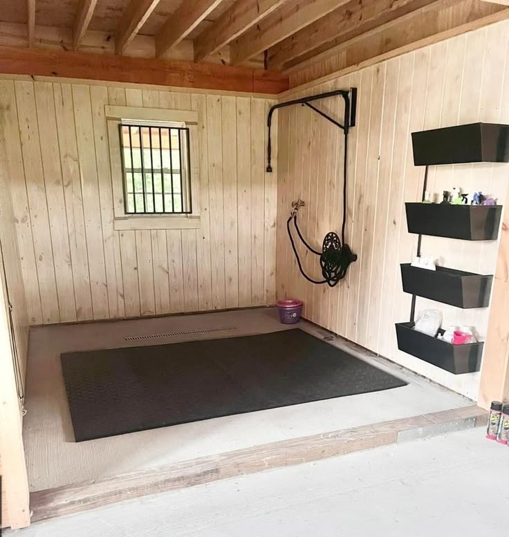 the inside of a shed with wood paneling and shelving on the walls, including an exercise mat