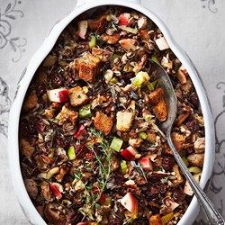 a bowl filled with stuffing and vegetables on top of a white table cloth next to a spoon