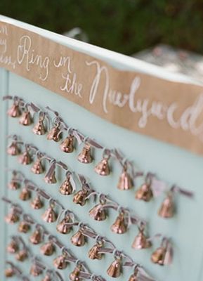 there are many small bells attached to the wall in front of this wedding ceremony sign