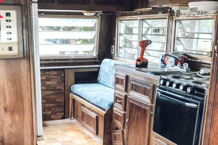 the inside of an rv with wood paneling and blue upholstered seat covers