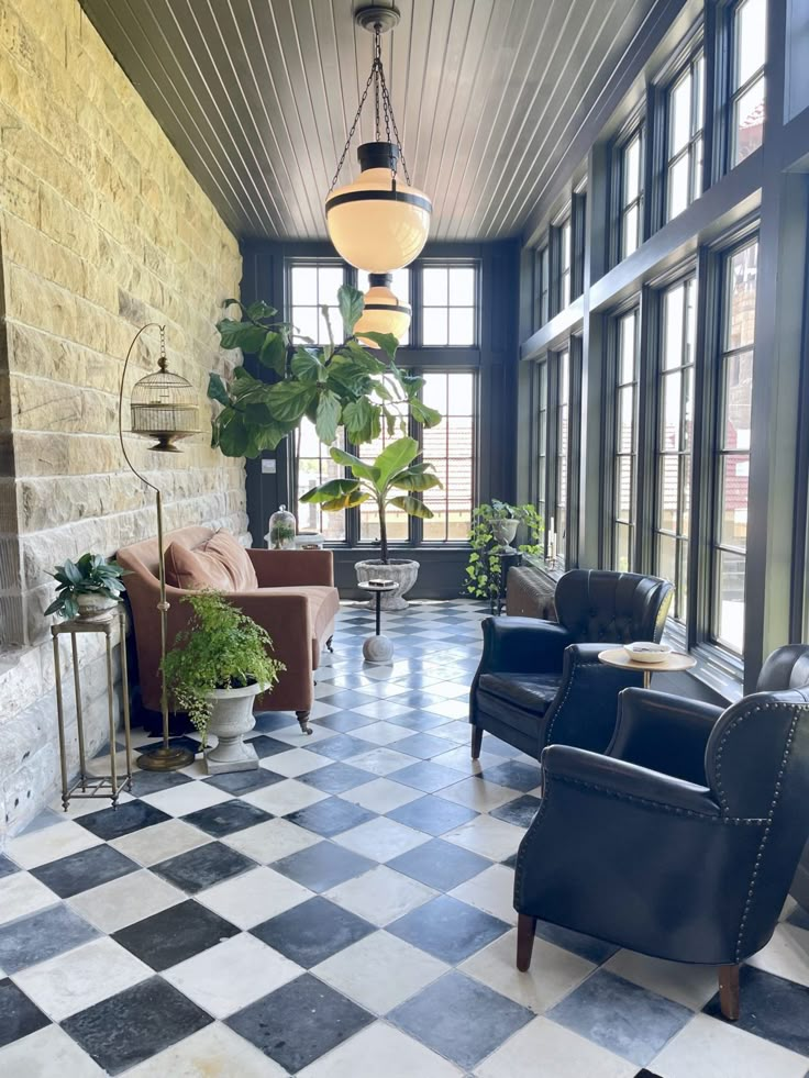 a living room with black and white checkered flooring, two leather chairs and a lamp hanging from the ceiling