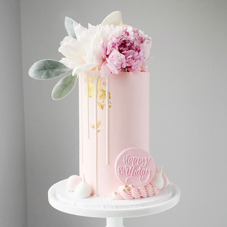 a pink birthday cake with flowers on top