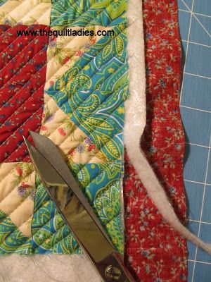 a pair of scissors sitting on top of a piece of fabric next to a quilt