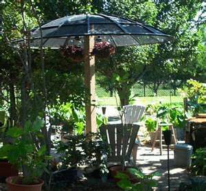 an umbrella in the middle of a garden with potted plants and chairs around it