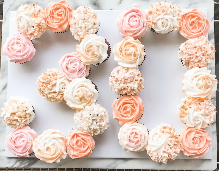 cupcakes decorated with pink and white frosting are arranged in the shape of the letter e