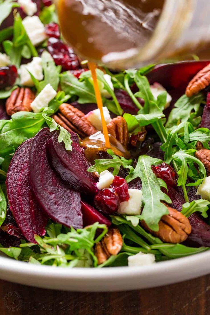 a salad with beets, carrots and feta cheese is being drizzled with dressing