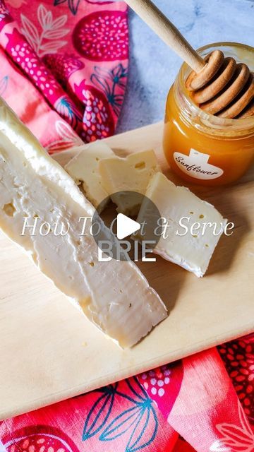 a wooden cutting board topped with cheese and honey