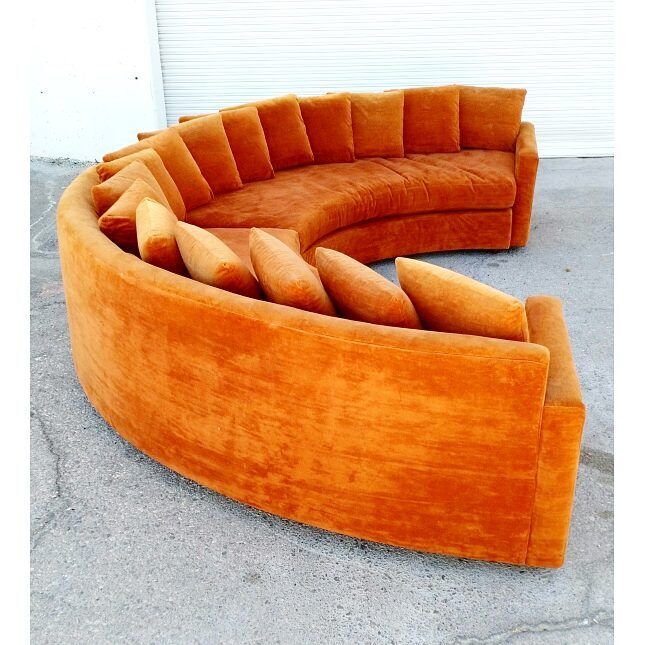 an orange curved couch sitting in front of a garage door