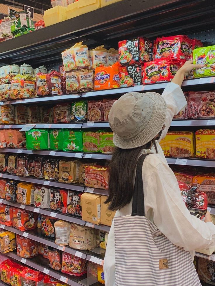 a woman in a hat is looking at the food on display behind her she's pointing to something