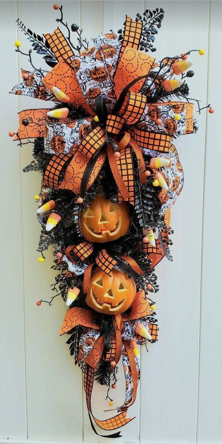 an orange and black mesh wreath with jack - o'- lantern faces on it