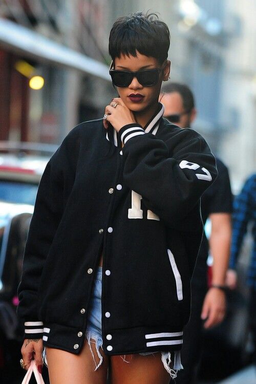 a woman walking down the street with a handbag in her other hand and wearing a black jacket