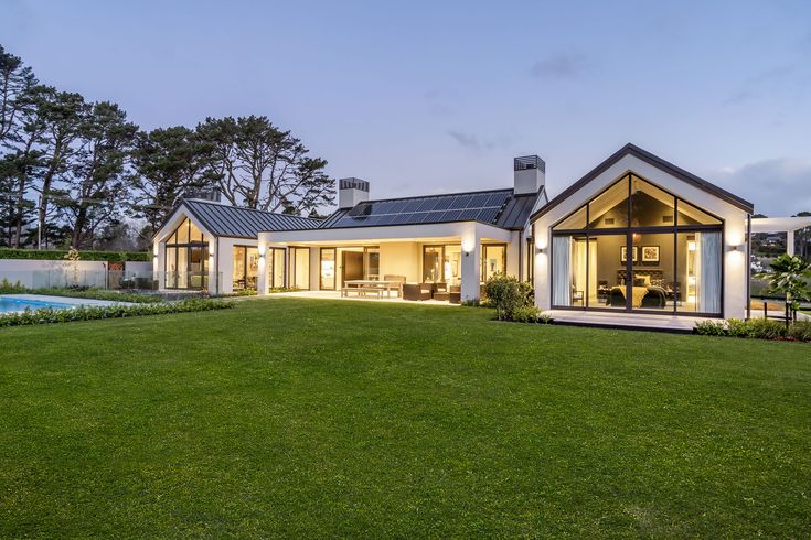 a house with a swimming pool in the middle of it's lawn area at dusk