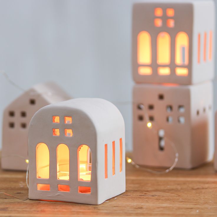 three lit up houses sitting on top of a wooden table