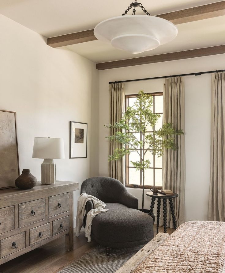 a bedroom with a bed, dresser and chair next to a window in the room