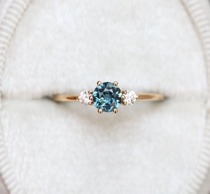 an engagement ring with a blue diamond surrounded by three diamonds