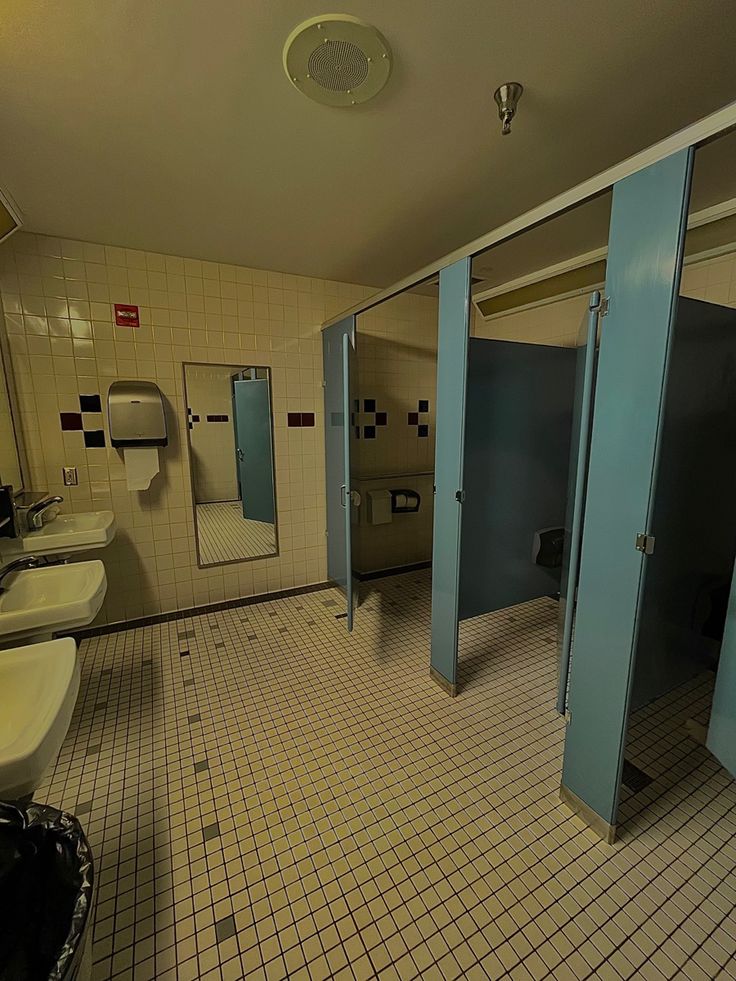 a bathroom with three stalls and two sinks