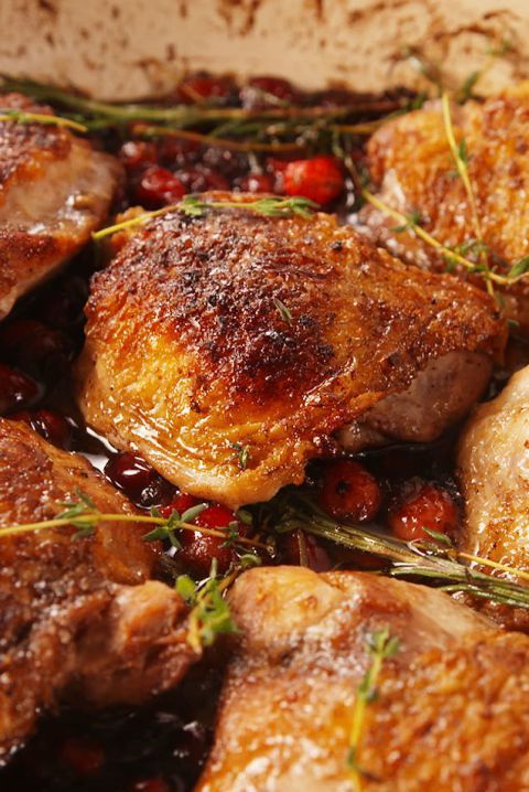 some meat is cooking in a pan with cranberries and herbs on the side