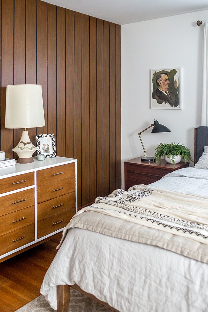 a bedroom with wood paneling and white bedding