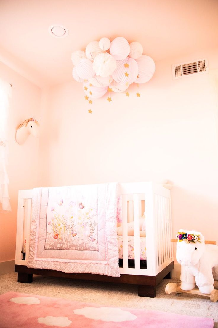 a baby crib in the corner of a room with balloons hanging from the ceiling