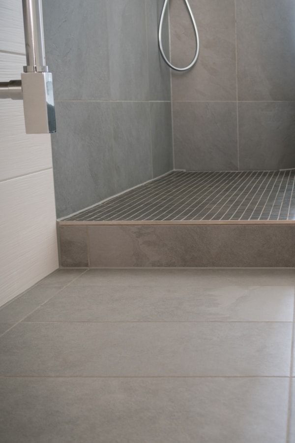 a bathroom with a walk in shower next to a toilet and tiled flooring area