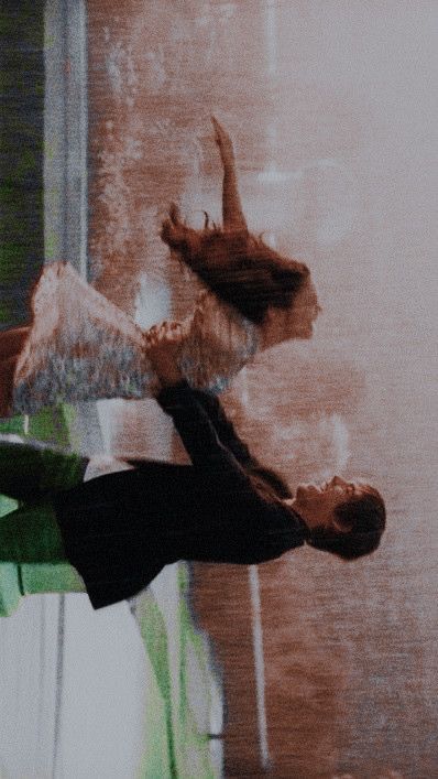 two people are dancing in front of a window