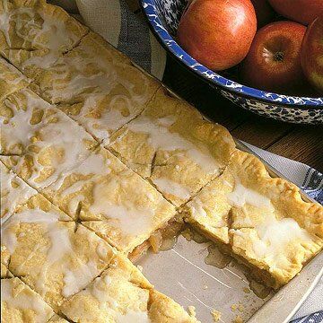 an apple pie is cut into pieces and sits next to a bowl full of apples