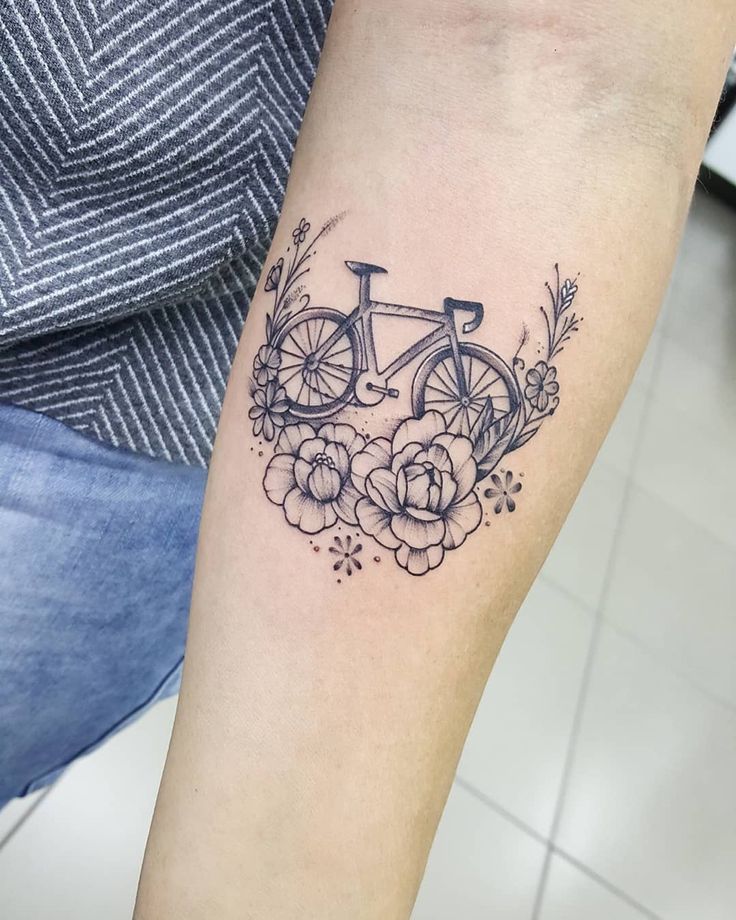 a woman's arm with a bicycle and flowers tattoo on it