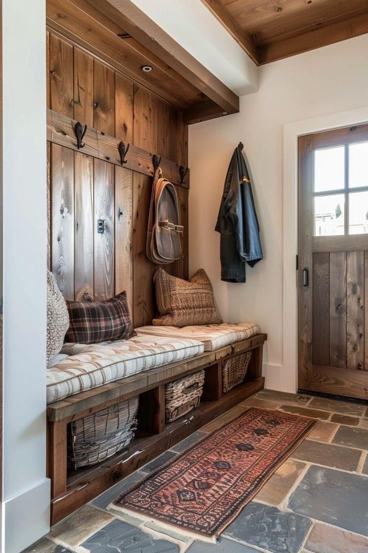 a wooden bench sitting in the middle of a room next to a door with hooks on it