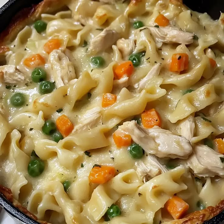 a casserole dish with chicken, noodles and peas