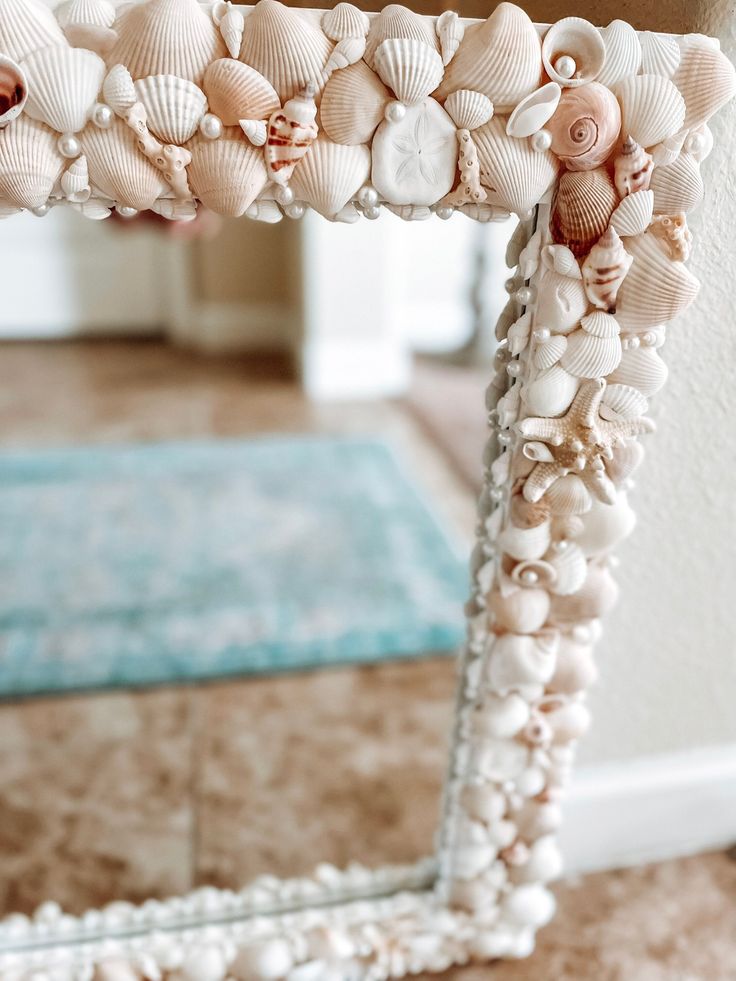 a mirror with seashells on it in front of a carpeted floor and wall