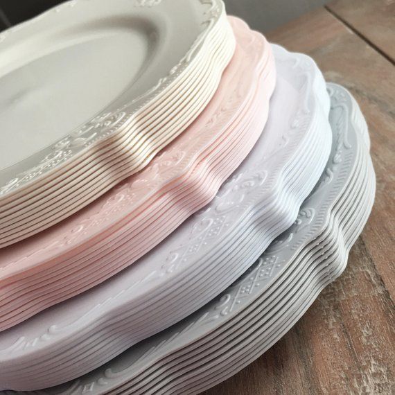 a stack of white and pink plates sitting on top of a wooden table