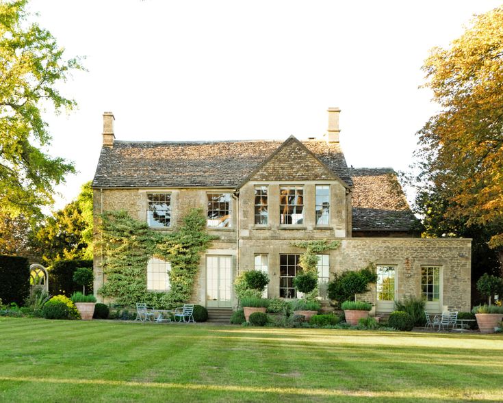 an old stone house with potted plants on the lawn