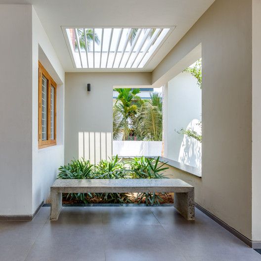 a bench sitting in the middle of a room next to a plant filled wall and windows