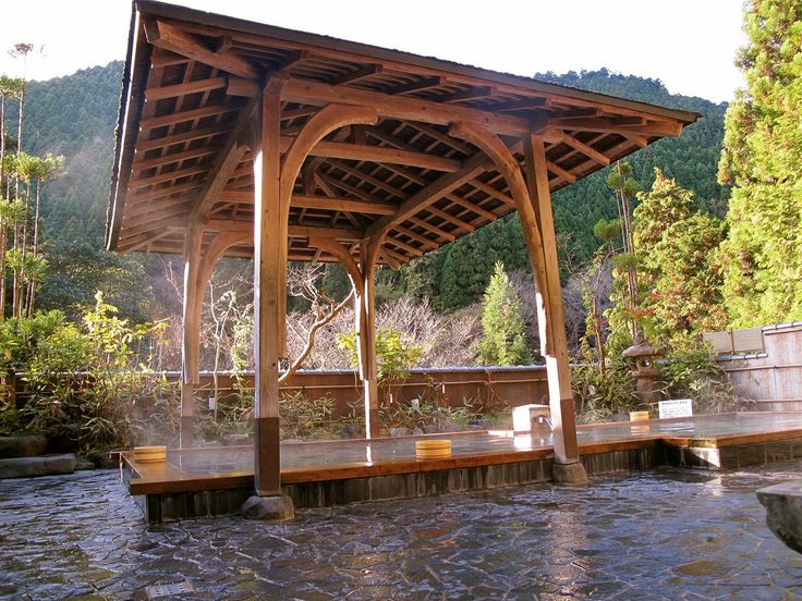 a wooden gazebo sitting on top of a river next to a lush green forest