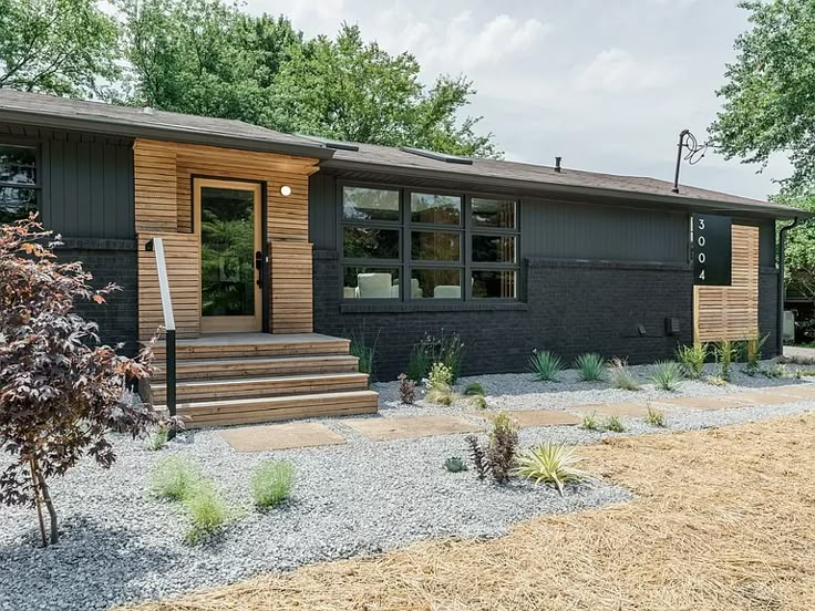 a black house with wooden siding and steps leading to the front door