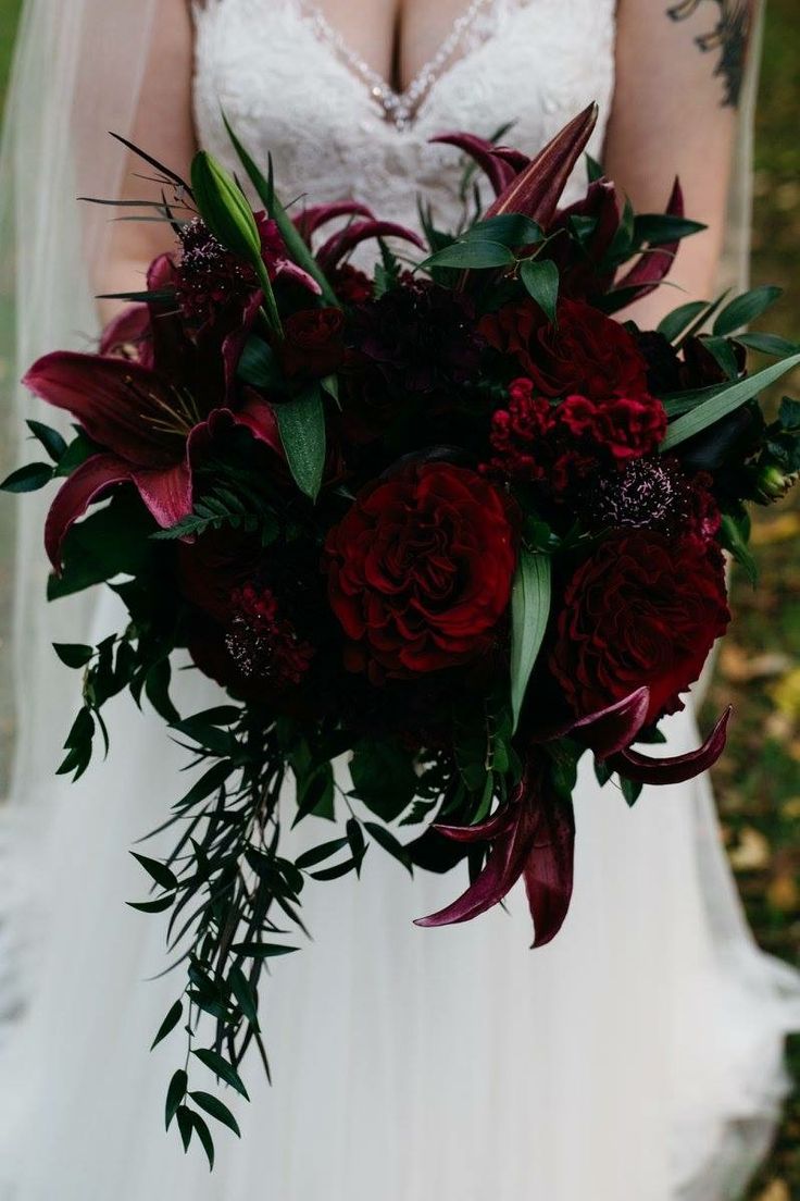 a bride holding a bouquet of red flowers