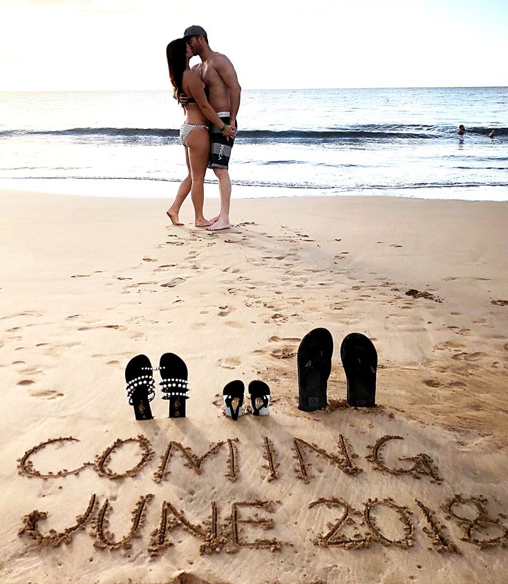 two people standing in the sand near some sandals