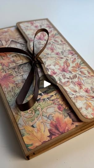 an open book with a ribbon tied around it's cover and the pages are covered in floral designs