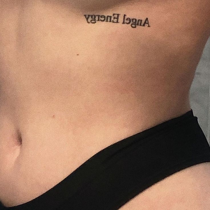 a woman's stomach with the word angel energy tattooed on her lower side,