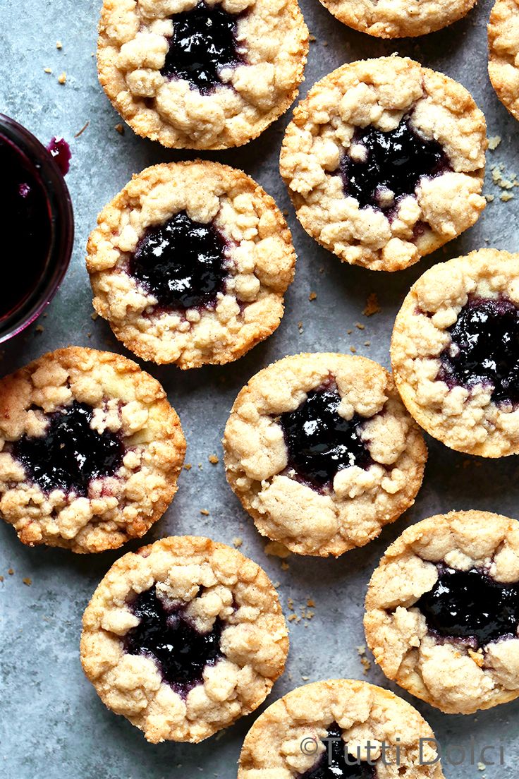 blueberry muffins are arranged on a table next to a glass of wine