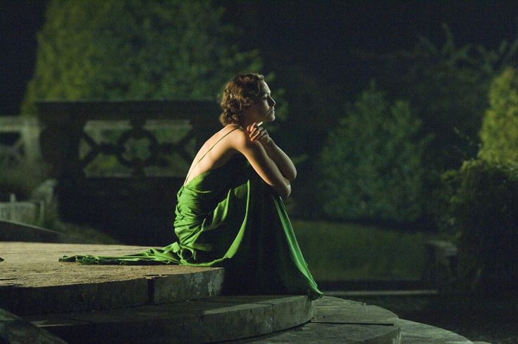 a woman in a green dress sitting on steps