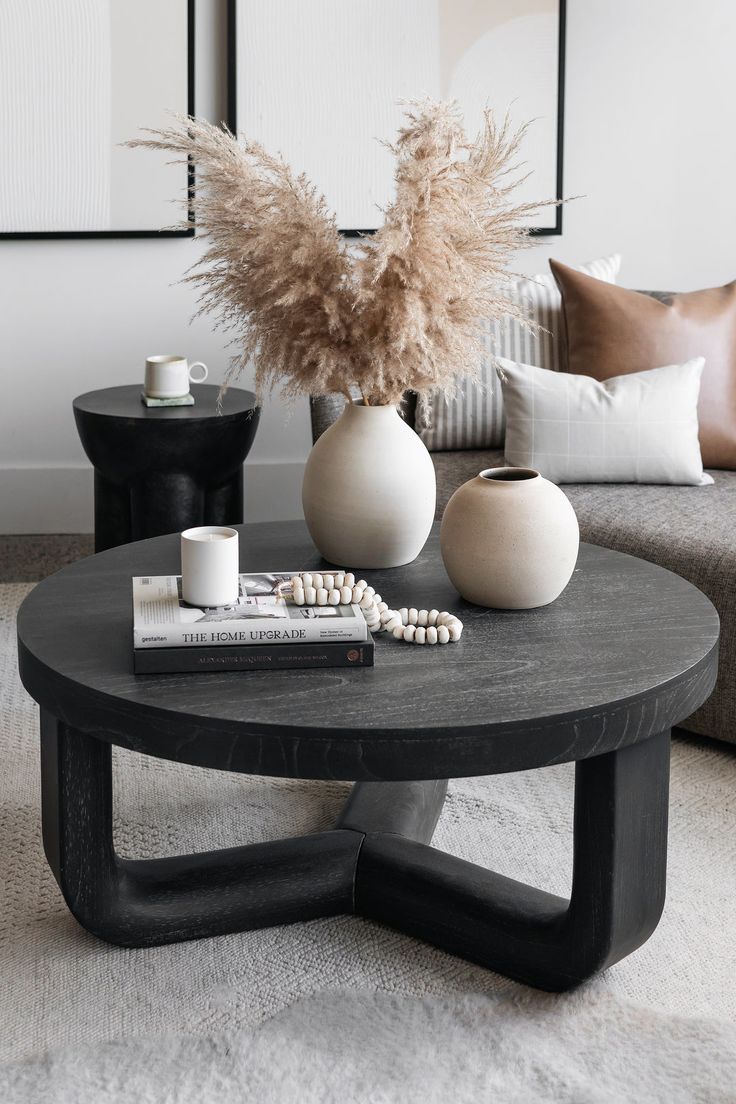 a coffee table with two vases and a book on it in front of a couch