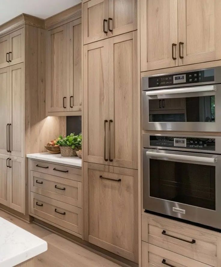 a large kitchen with wooden cabinets and stainless steel ovens in the center, along with marble counter tops